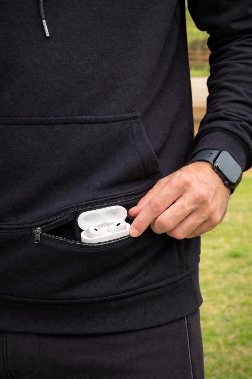 Black travel hoodie with hidden zip pocket holding wireless airpods
